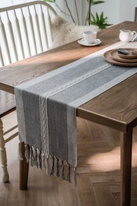 Detail of Nordic jacquard table runner with geometric embroidery and handmade tassels