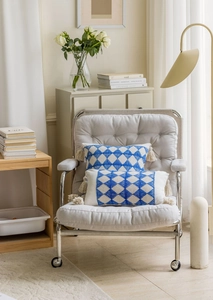 Detail of two jacquard throw pillows with blue geometric patterns and cream tassels