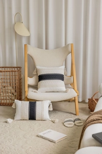 Detail of bohemian jacquard pillow with black stripes and tassel accents on a chair