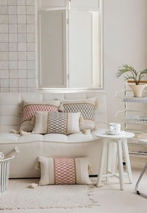 Detail of bohemian cream pillow with geometric embroidery and tassels in a cozy setting