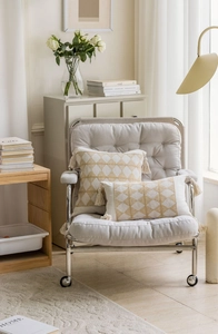 Detail of yellow geometric jacquard cushion with elegant tassels on a stylish chair