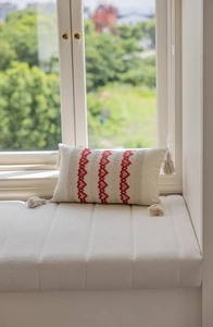 Detailed view of cream lumbar pillow with red heart embroidery and corner tassels