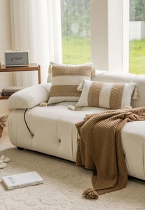 Detail of knit throw blanket and tassels on brown and beige jacquard cushions