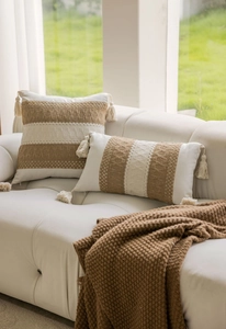 Detail of bohemian jacquard pillow with tassels and striped texture on leather sofa