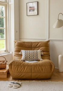 Caramel Togo style leather lounge chair with a boho embroidered lumbar pillow