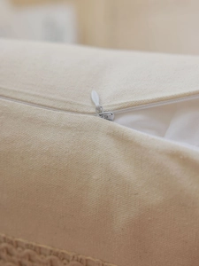 Detail of invisible zipper and woven fringe on cream jacquard cushion cover fabric
