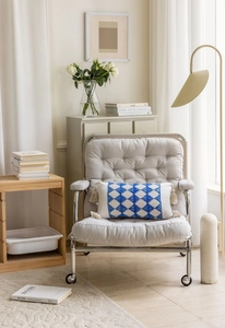 Close-up of bohemian lumbar pillow with blue diamond pattern and tassels on modern chair