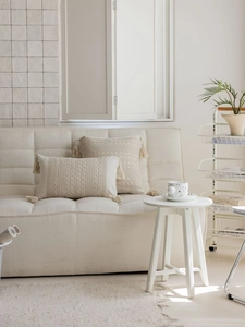 Detailed view of cream jacquard throw pillow covers with woven texture and corner tassels