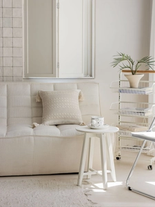 Detail of cream jacquard throw pillow featuring geometric knitting and elegant corner tassels