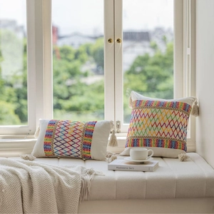 Bohemian style embroidered geometric cushion cover with tassels on a bright windowsill