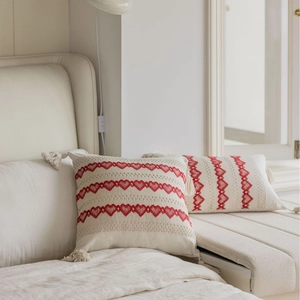 Beige jacquard sofa cushion with red embroidered hearts and decorative corner tassels