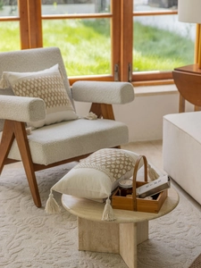 Detail eines cremefarbenen Boho-Kissenbezugs mit Webmustern und dekorativen Quasten