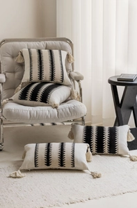 Detail of four-piece jacquard pillows with geometric black stripes and thick corner tassels