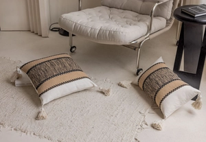 Detail of bohemian striped woven pillowcase with tassels in cream, brown, and black colors