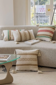 Dettaglio di federa jacquard bohémien con motivi etnici e nappine decorative sui bordi