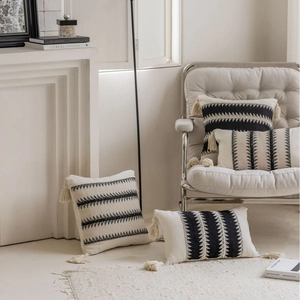 Bohemian woven throw pillows with black geometric patterns and handmade tassels on a chair