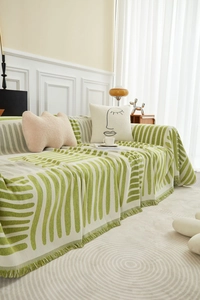 Gedetailleerde close-up van groen-witte gebreide bankplaid met decoratieve korte kwastjes