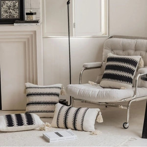 Bohemian knit throw pillow covers with black geometric patterns and tassels on a chair