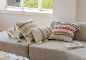 Dettaglio di federe per cuscini boho con ricami colorati e nappe decorative