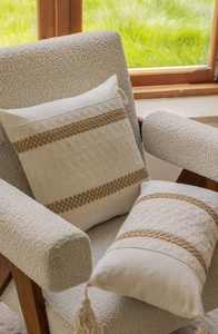 Detail of cream jacquard throw pillows with brown stripes and decorative tassels on a sofa