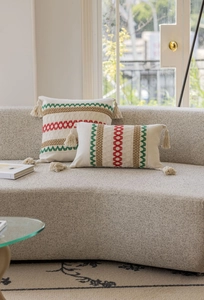 Dettaglio dei copricuscini boho con ricami colorati e nappe fatte a mano sul divano