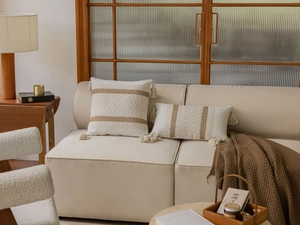 Detail of bohemian style beige throw pillows with brown stripes and tassels on a sofa