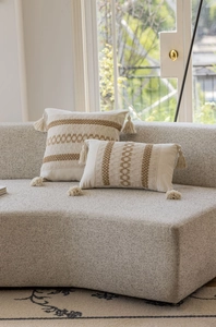 Dettaglio del cuscino boho in tessuto con motivi geometrici marroni e nappe decorative
