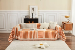 Detail van een dikke oranje en beige geometrische gebreide deken met franjes