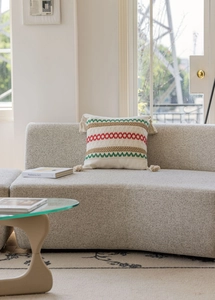 Dettaglio del ricamo geometrico e delle nappe corte su una fodera per cuscino beige