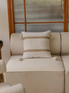 Detailed view of bohemian cream woven pillowcase featuring fringe and brown stripe accents