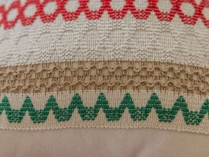 Dettaglio del ricamo jacquard e del pizzo all'uncinetto sulla federa del cuscino beige