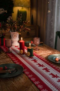 Close-up of red reindeer and snowflake jacquard table runner on a wooden surface