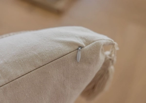 Dettaglio ravvicinato della cerniera invisibile e della trama del copricuscino beige