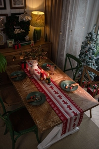 Detailed close-up of a red knitted Christmas runner with white reindeer and snowflake motifs