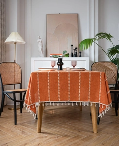 Détail de la nappe en lin orange brûlé avec broderies blanches et bordures à franges élégantes