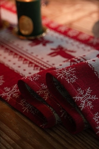 Close-up of red and white Christmas table runner with knitted reindeer and snowflakes