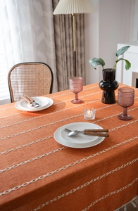 Détail de nappe en coton orange avec motifs géométriques blancs et bords à franges