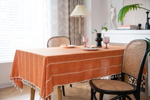 Détail de la nappe en lin orange avec broderie géométrique blanche et bordure à franges