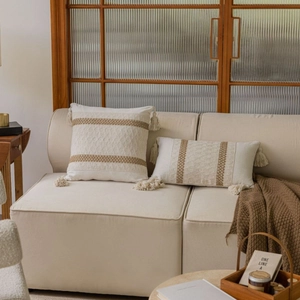 Bohemian woven throw pillows with tassels and ochre stripes on a cream sofa