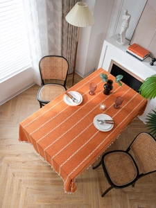 Détail d'une nappe en coton et lin orange avec broderie géométrique et glands