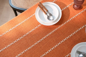 Détail d'une nappe en coton lin terracotta avec broderie blanche et texture tissée