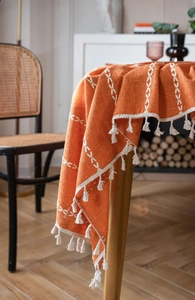 Détail d'une nappe orange en coton et lin avec broderie croisée blanche et franges