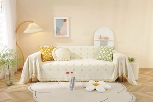 Detail of cream woven sofa cover with yellow checkered patterns and fringe edges