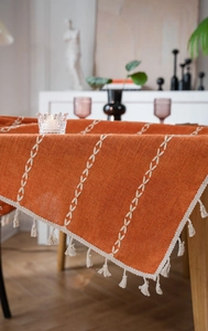 Détail de nappe en coton lin orange avec broderie chevronnée blanche et pompons décoratifs