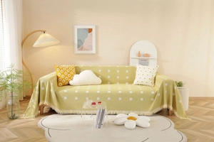 Close-up of geometric jacquard pattern and tassel edges on sage green sofa cover