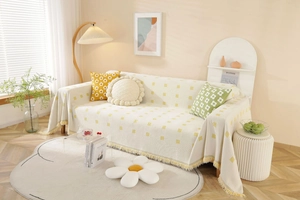 Detail of cream sofa cover with yellow geometric jacquard pattern and tassel fringes