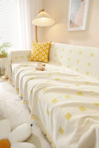 Detail of thick cream knit sofa throw with yellow geometric squares and fringe tassels