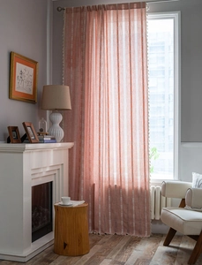 Détail des rideaux rayés rose saumon avec broderie blanche et bordure à franges