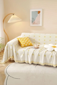 Close-up of geometric cream and yellow knitted throw blanket with fringe edges and pillows