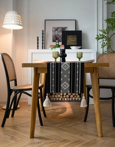 Close-up of bohemian woven table runner featuring black and white geometric patterns with tassels
